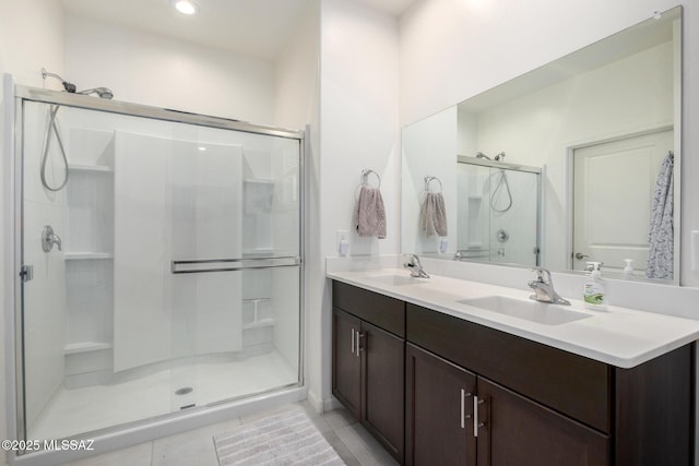 full bath featuring double vanity, tile patterned flooring, a stall shower, and a sink