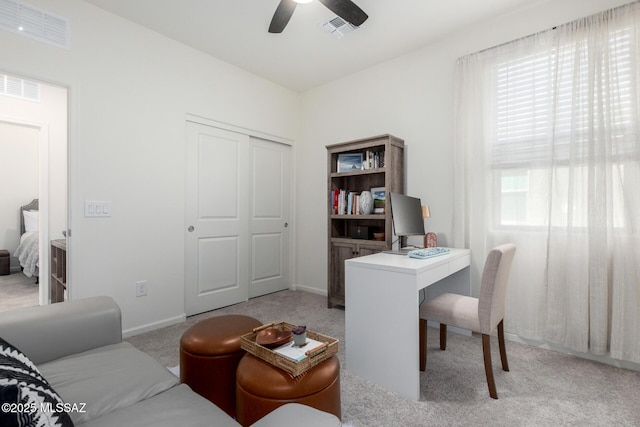 home office with light carpet, visible vents, and a healthy amount of sunlight