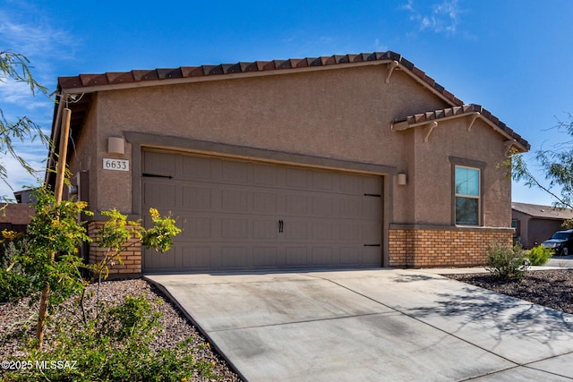 view of front of property featuring brick siding, a tile roof, stucco siding, driveway, and an attached garage