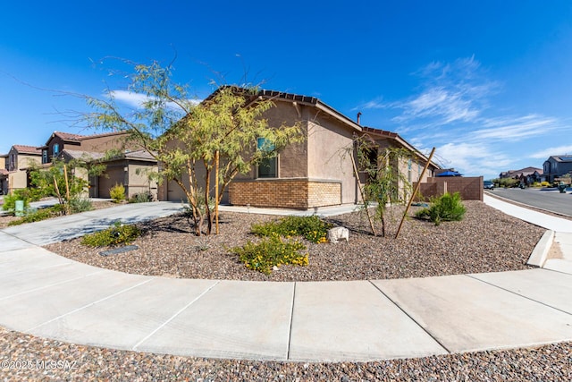 view of front of home featuring a residential view, stucco siding, concrete driveway, a tiled roof, and brick siding