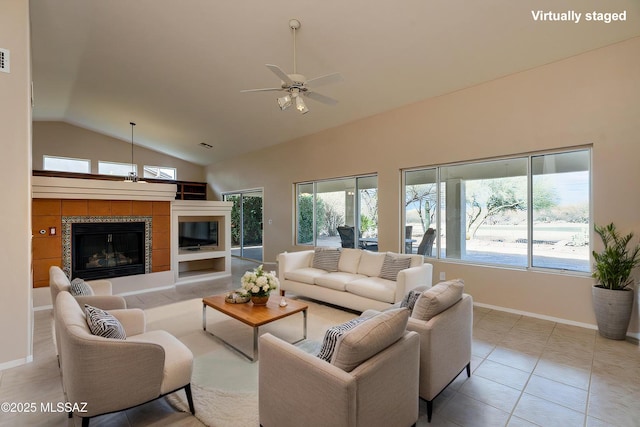 tiled living area with baseboards, high vaulted ceiling, ceiling fan, and a tiled fireplace