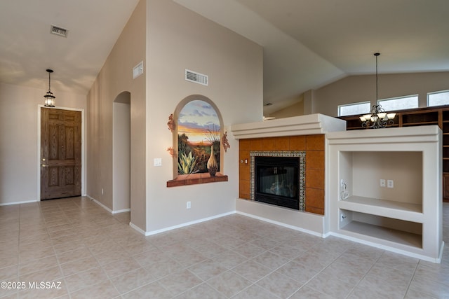unfurnished living room featuring visible vents, lofted ceiling, arched walkways, a tile fireplace, and a chandelier