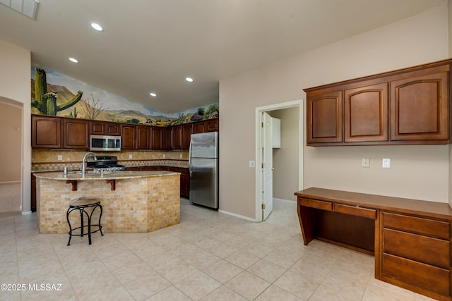 kitchen with a breakfast bar area, light stone countertops, visible vents, stainless steel appliances, and tasteful backsplash