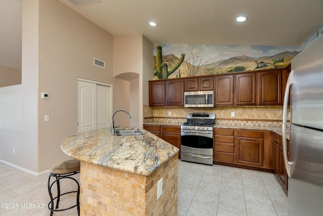 kitchen with light tile patterned flooring, appliances with stainless steel finishes, light stone countertops, and a sink