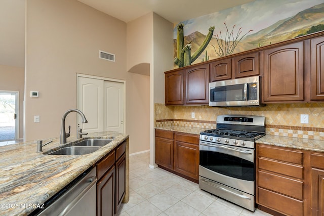 kitchen featuring visible vents, light stone countertops, appliances with stainless steel finishes, light tile patterned flooring, and a sink
