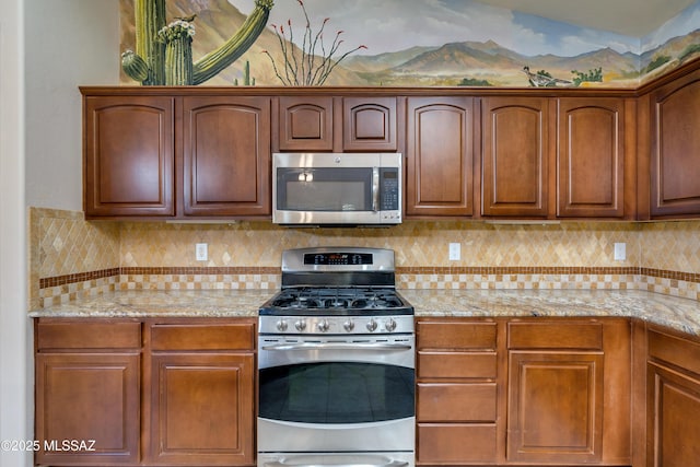 kitchen featuring stainless steel appliances, light stone countertops, tasteful backsplash, and brown cabinets