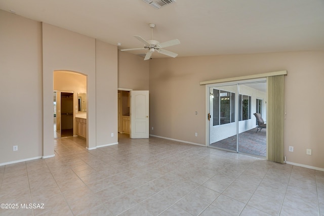 interior space with light tile patterned floors, a ceiling fan, visible vents, baseboards, and arched walkways