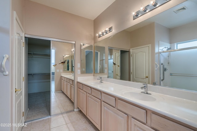 bathroom featuring double vanity, a stall shower, visible vents, and a sink