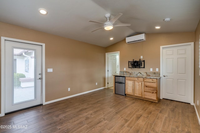kitchen featuring fridge, wood finished floors, a ceiling fan, and a wall mounted AC
