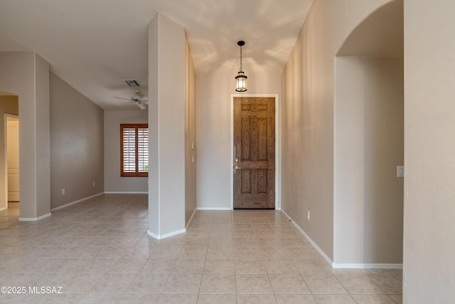foyer entrance featuring visible vents, arched walkways, light tile patterned floors, baseboards, and ceiling fan