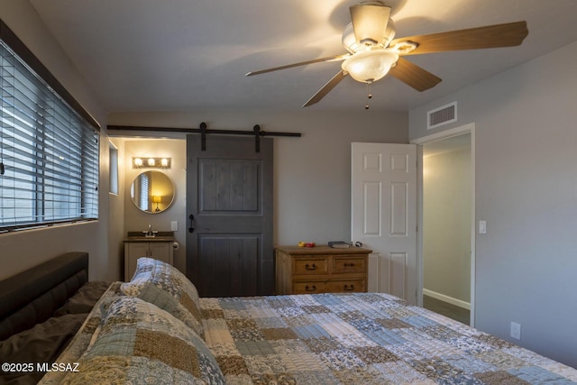 bedroom featuring a barn door, a ceiling fan, and visible vents