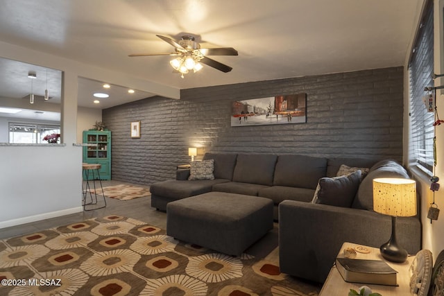 living area featuring brick wall, baseboards, and a ceiling fan