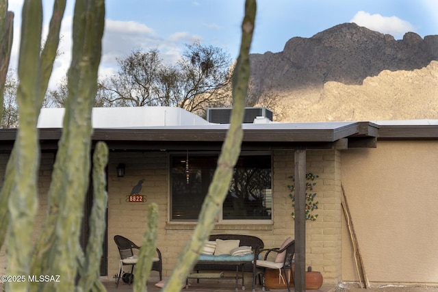 exterior space with a mountain view, central AC unit, and stucco siding