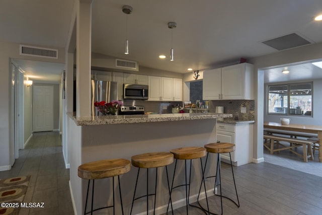 kitchen featuring white cabinets, backsplash, visible vents, and appliances with stainless steel finishes