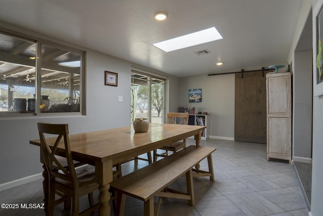 dining space featuring visible vents, a barn door, a skylight, light tile patterned floors, and baseboards