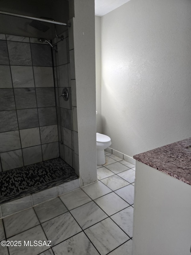 bathroom with tile patterned flooring, toilet, baseboards, and a stall shower