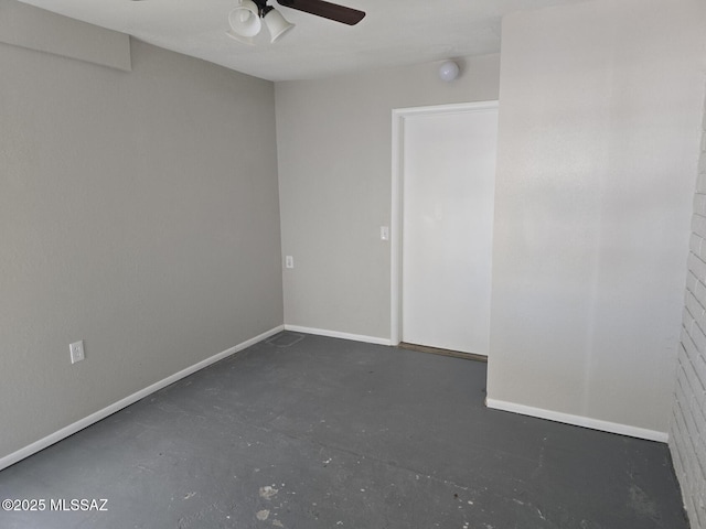 spare room with a ceiling fan, concrete flooring, and baseboards