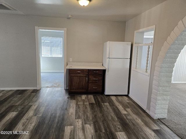 kitchen featuring dark wood-style floors, freestanding refrigerator, light countertops, baseboards, and dark brown cabinets