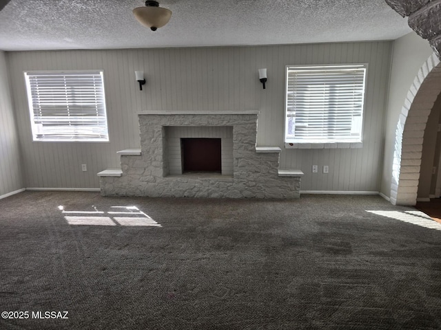 unfurnished living room with a wealth of natural light, carpet floors, a textured ceiling, and a fireplace