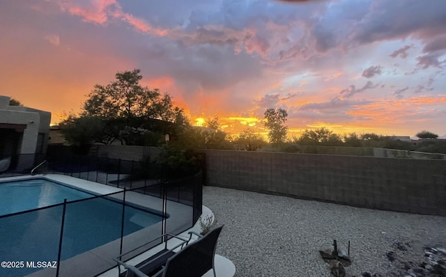 pool at dusk with a fenced in pool, a patio area, and a fenced backyard
