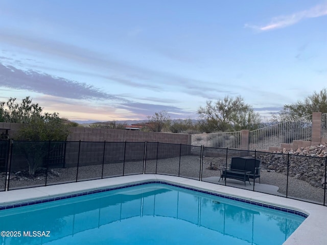 pool at dusk featuring a fenced backyard and a fenced in pool