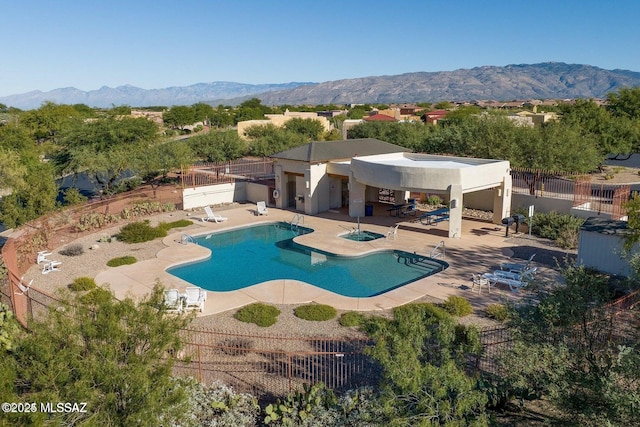 community pool featuring fence, a patio, and a mountain view