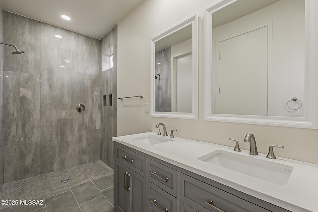 full bathroom with a sink, tiled shower, and double vanity