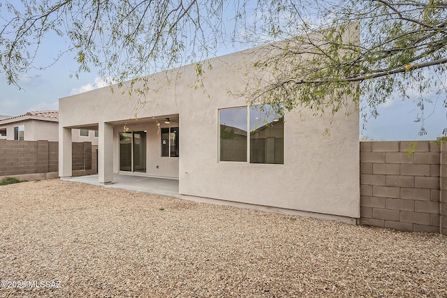 rear view of property featuring a patio, a fenced backyard, and stucco siding