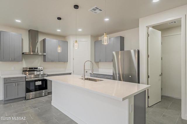 kitchen with appliances with stainless steel finishes, gray cabinetry, wall chimney range hood, and a sink