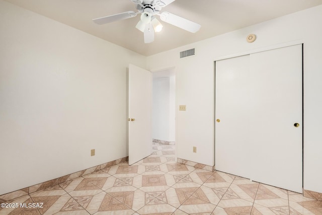 unfurnished bedroom with visible vents, a closet, light tile patterned flooring, and a ceiling fan