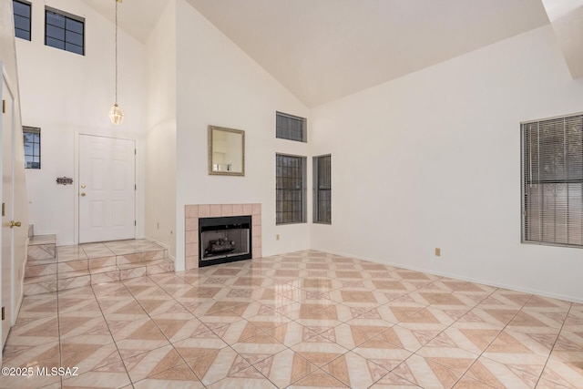 unfurnished living room with light tile patterned floors, visible vents, baseboards, high vaulted ceiling, and a tiled fireplace