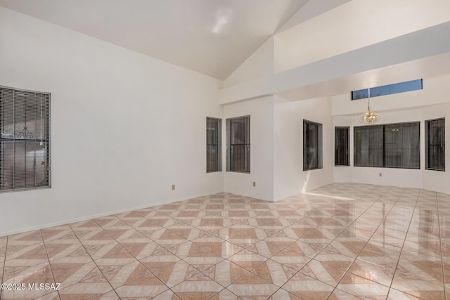 empty room with light tile patterned floors, baseboards, and high vaulted ceiling