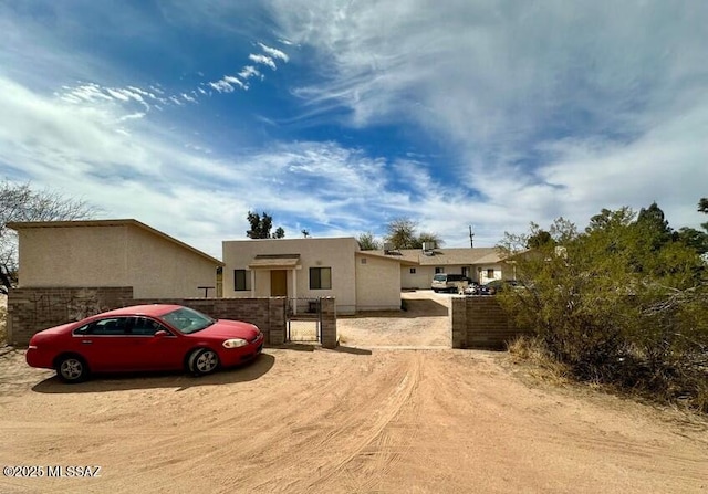 view of front of property featuring a gate, stucco siding, and fence