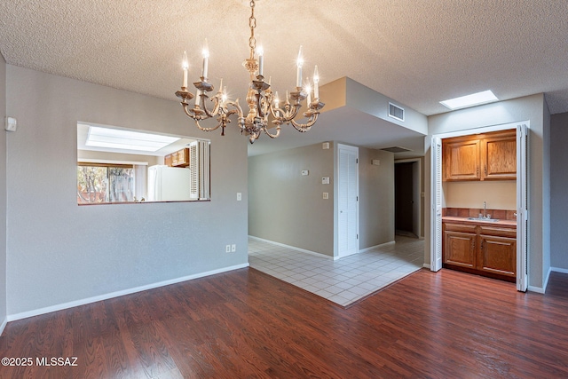 interior space with visible vents, a sink, a textured ceiling, and wood finished floors