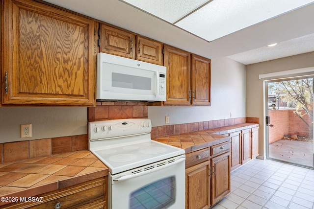 kitchen featuring tile countertops, white appliances, and brown cabinetry