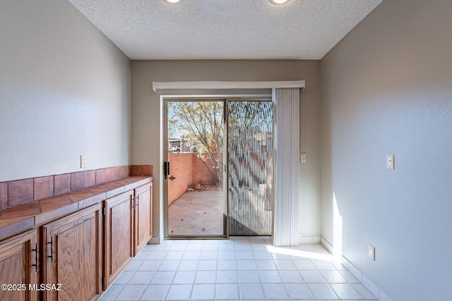 doorway to outside with light tile patterned floors and a textured ceiling