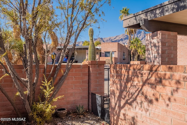 view of home's exterior featuring a gate, a mountain view, brick siding, and fence