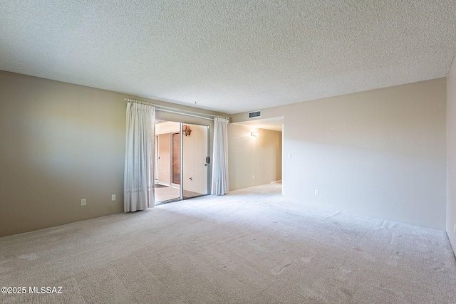 carpeted spare room featuring visible vents and a textured ceiling