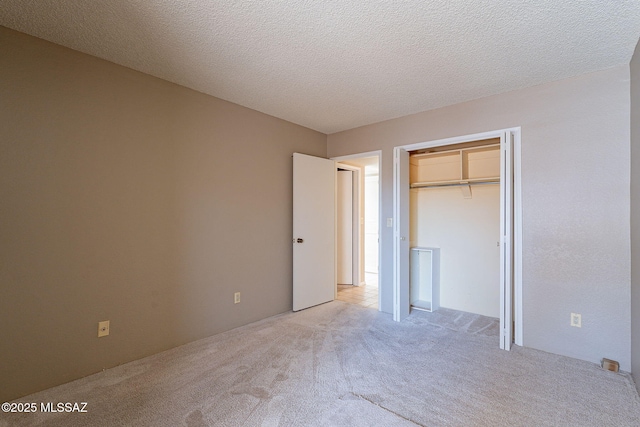 unfurnished bedroom featuring a closet, light colored carpet, and a textured ceiling