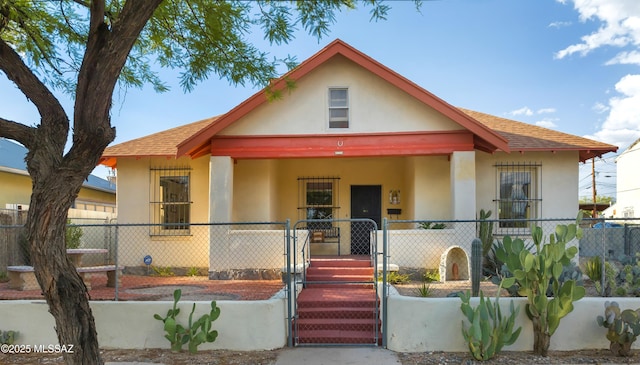 view of front of home with roof with shingles, a gate, a fenced front yard, and stucco siding