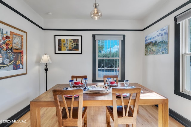 dining space with baseboards and light wood-style flooring