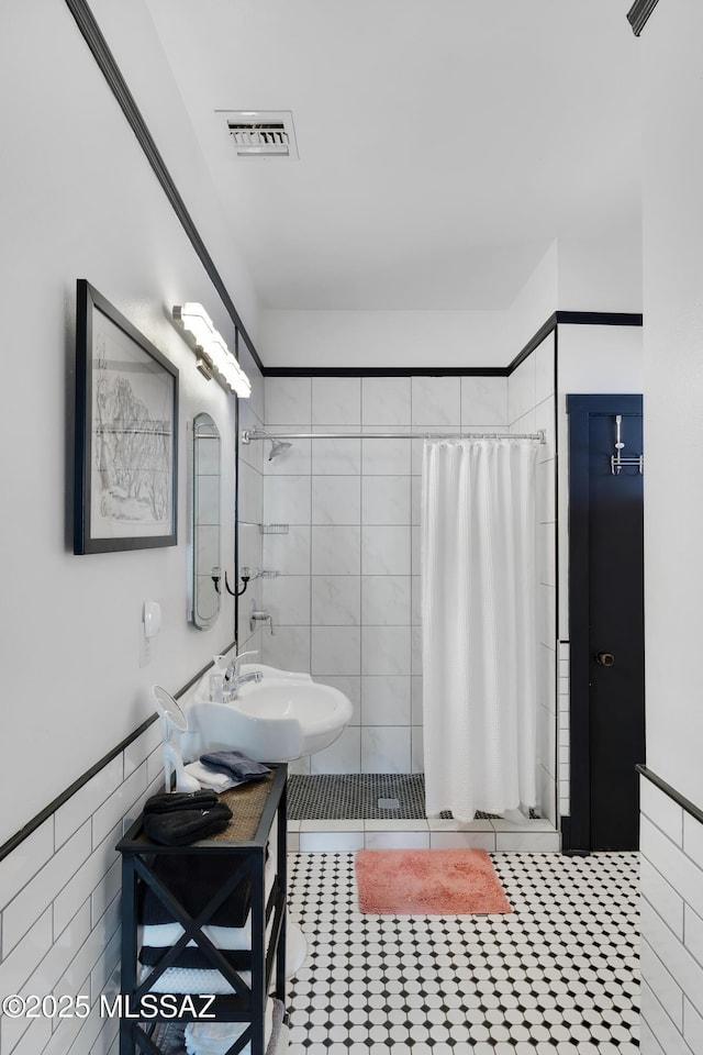 full bath featuring visible vents, a stall shower, a sink, tile patterned flooring, and tile walls