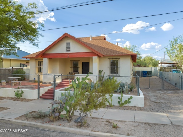 bungalow-style home with a porch, a gate, a fenced front yard, and stucco siding