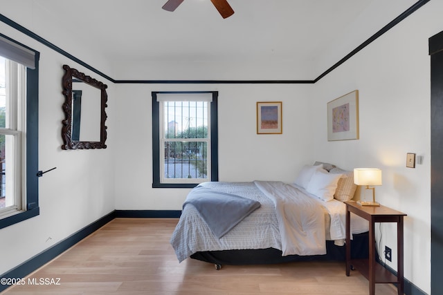 bedroom with a ceiling fan, baseboards, and wood finished floors