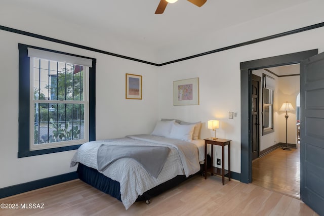 bedroom with baseboards, light wood-style flooring, and a ceiling fan