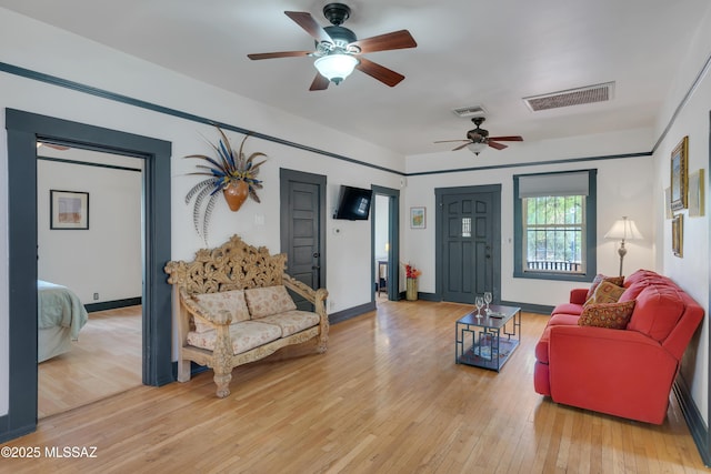 living area featuring visible vents, baseboards, light wood-type flooring, and ceiling fan