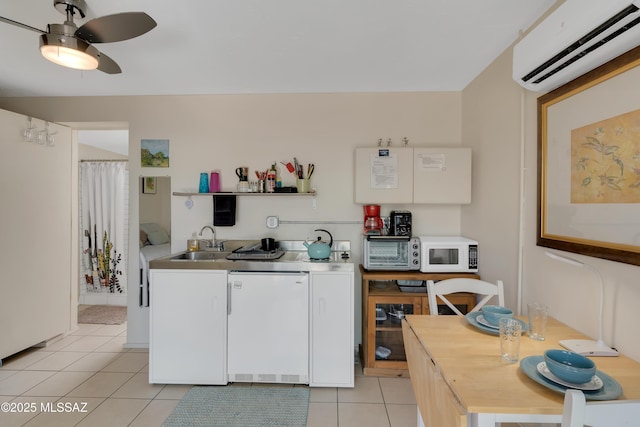 kitchen with a wall unit AC, white microwave, light tile patterned flooring, ceiling fan, and a sink