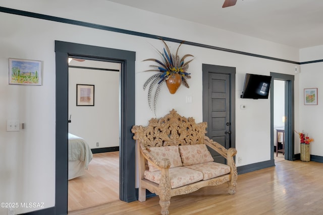 living area with baseboards, a ceiling fan, and light wood finished floors