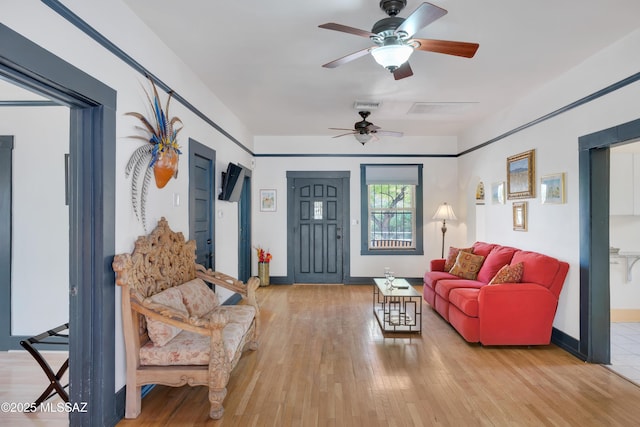 living area featuring baseboards, wood finished floors, visible vents, and ceiling fan