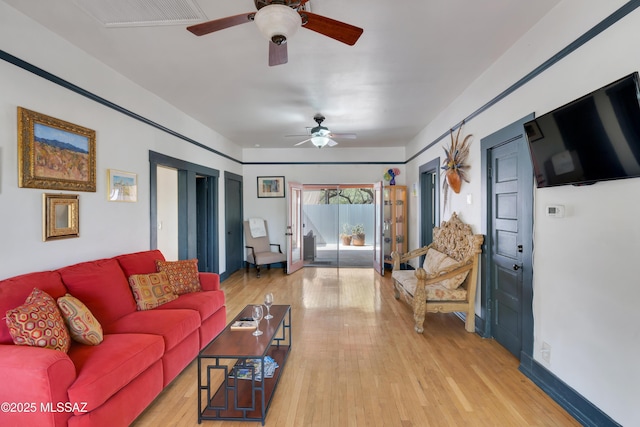 living room with wood finished floors, a ceiling fan, baseboards, and visible vents